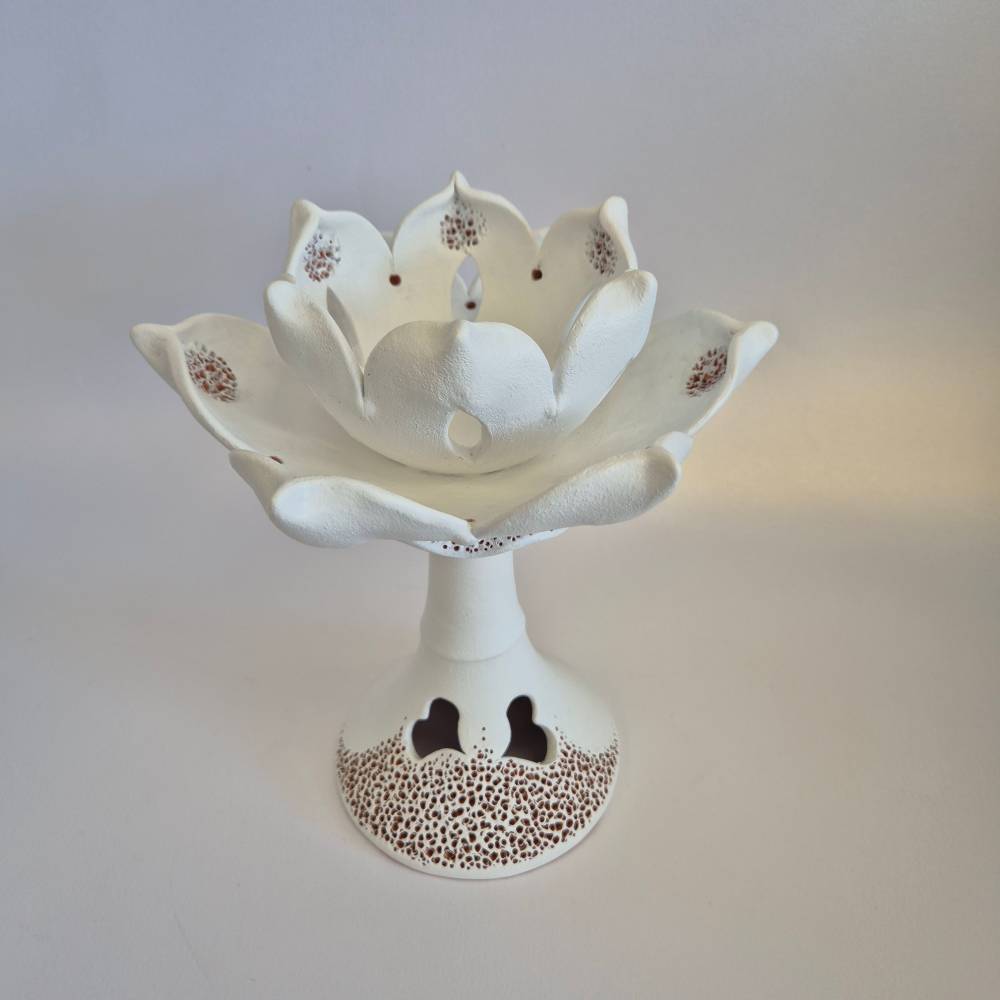 Seimos-zidinys-zvakide_Keramikinis-lotoso-ziedas-ant-kojeles_3_salonassandrijlt_ White ceramic lotus flower sculpture on a pedestal, used as a decorative centerpiece.