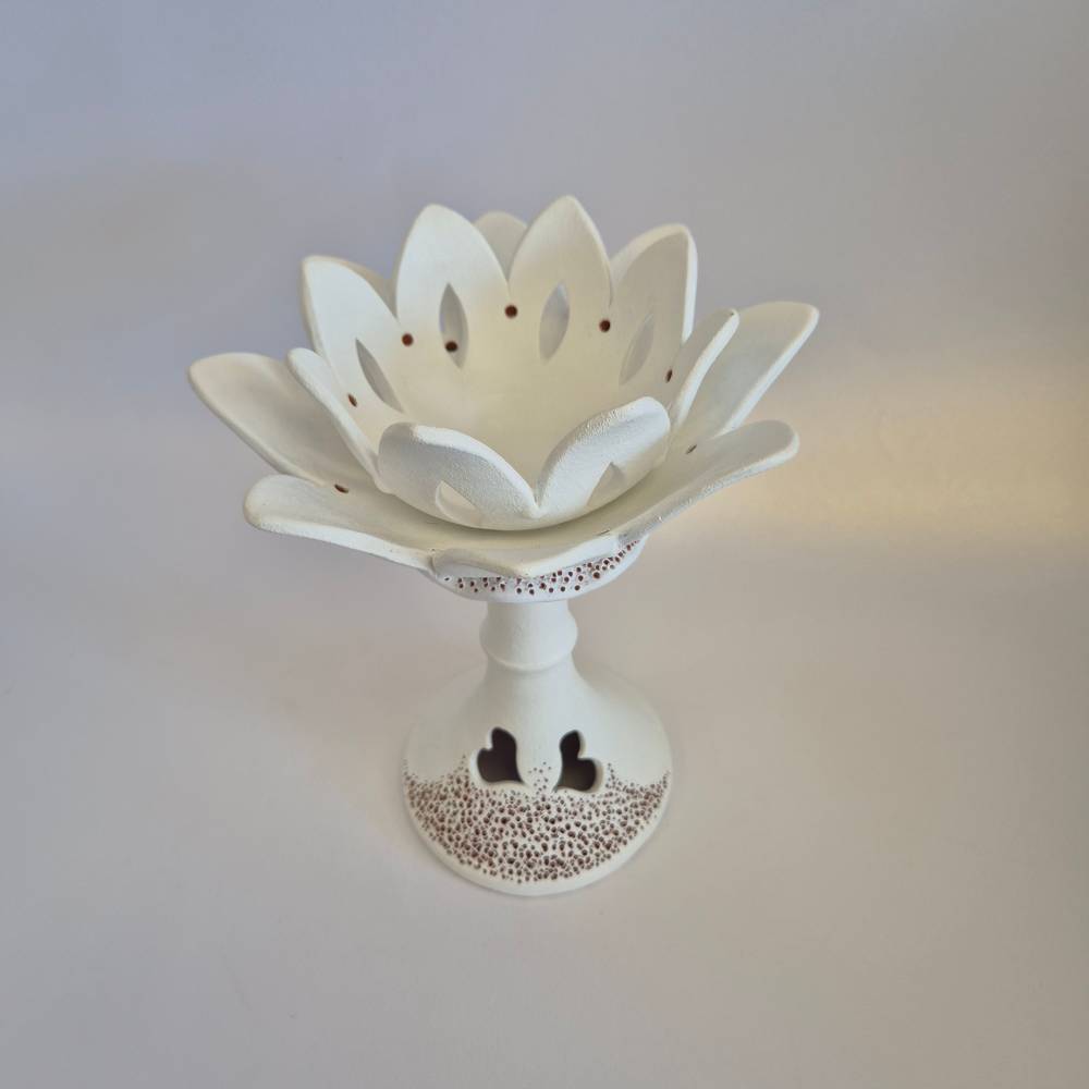 Seimos-zidinys-zvakide_Keramikinis-lotoso-ziedas-ant-kojeles_4_salonassandrijlt_ White ceramic lotus flower on a pedestal, with perforated base and heart-shaped cutouts.