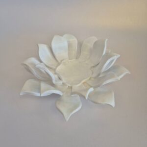 White ceramic flower wall sculpture resembling a blooming lotus on a pale background, decorative artwork.